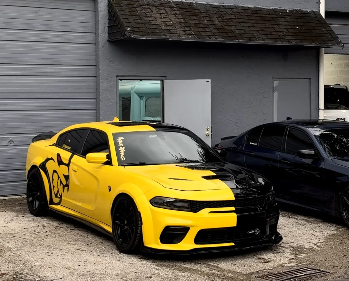 Fima’s yellow and black Dodge Charger Hellcat Widebody parked in front of the shop’s roll-up doors